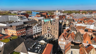 Luftaufnahme einer Stadt mit historischen Gebäuden und einem Fluss im Hintergrund.