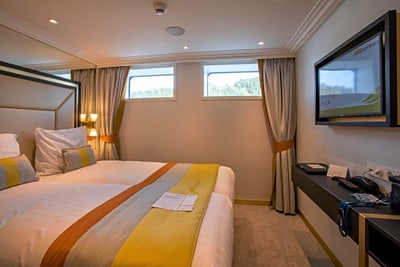 Modernes Hotelzimmer mit Bett, Fenstern und Fernseher.