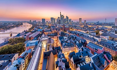 Stadtpanorama bei Sonnenuntergang mit Fluss und modernen Gebäuden.