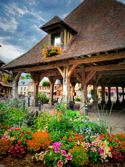 Historischer überdachter Markt mit bunten Blumen im Vordergrund.