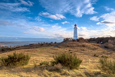 Leuchtturm auf einem Hügel mit Blick auf das Meer.