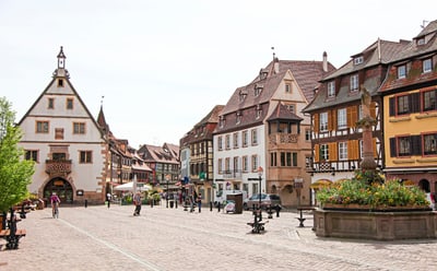 Historischer Platz mit alten Fachwerkhäusern und Springbrunnen.