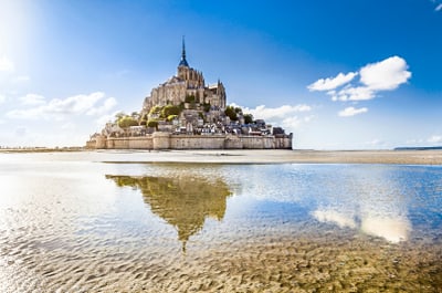 Le Mont-Saint-Michel bei Ebbe mit Spiegelung im Wasser.