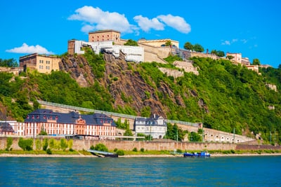 Festung auf Hügel über Flussufer bei klarem Himmel.