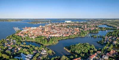 Luftaufnahme einer Altstadt auf einer Halbinsel am Wasser.