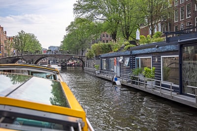 Bootsfahrt entlang einer Amsterdamer Gracht mit Hausbooten.