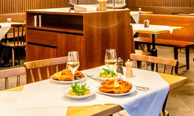 Zwei Teller mit paniertem Fleisch und Beilagen auf einem Tisch in einem Restaurant.
