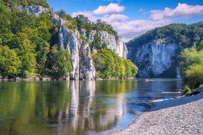 Fluss mit Felsen und Bäumen an einem sonnigen Tag.
