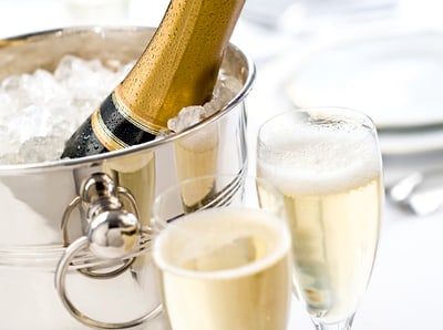 Nahaufnahme einer Flasche Champagner in einem Eiskübel mit zwei gefüllten Sektgläsern.