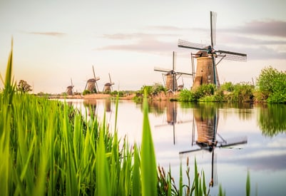 Windmühlen am Flussufer bei Sonnenuntergang.