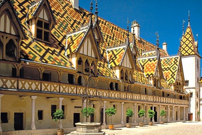 Historisches Gebäude mit buntem Ziegeldach und spitzen Giebeln.