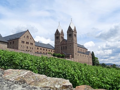 Benediktinerabtei mit Weinberg im Vordergrund.