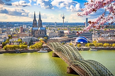 Stadtansicht mit Dom, Brücke und blühenden Zweigen.
