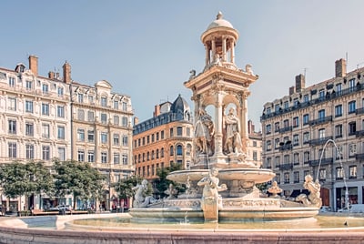 Historischer Brunnen auf einem städtischen Platz mit umliegenden Gebäuden.