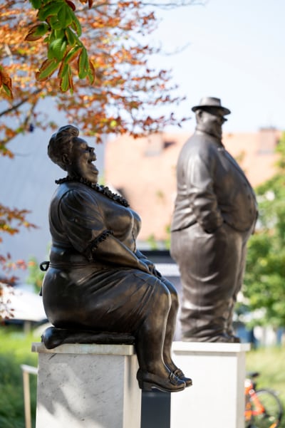 Bronzestatuen eines sitzenden Paares im Freien.