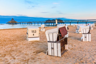 Strandkörbe am Strand mit Seebrücke bei Sonnenuntergang.