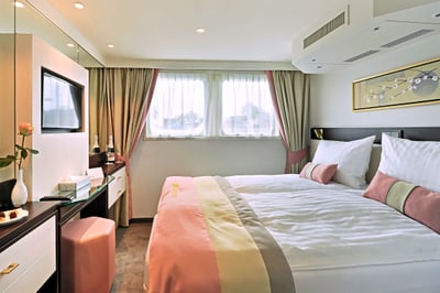 Helles Hotelzimmer mit Doppelbett, TV und Fenster.