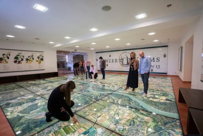 Menschen betrachten grosse Bodenkarte in Museumsausstellung.