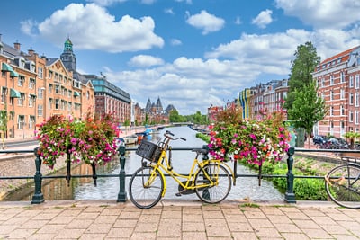 Gelbes Fahrrad auf Brücke vor Kanal und blühenden Blumen in Stadt.
