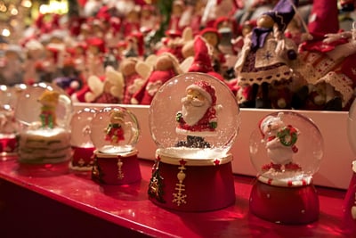 vier-staedte-maerchenhaft-magisch-8.jpg Weihnachtsschneekugeln mit Weihnachtsmann- und Engelmotiven auf rotem Tisch.