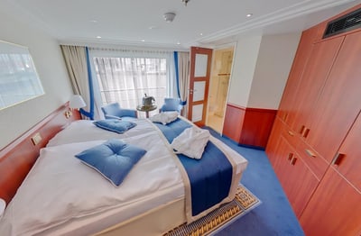 Elegantes Schlafzimmer mit Doppelbett, blauen Akzenten und Holzmöbeln.