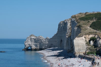 Küstenlandschaft mit Felsen und Strand, Menschen geniessen das Meer.
