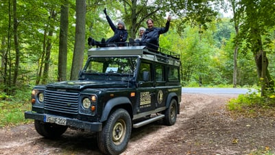 Drei Personen auf einem Geländewagen im Wald.