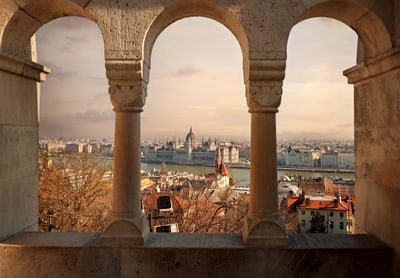 Ausblick durch Bögen auf Stadt und Fluss bei Sonnenuntergang.