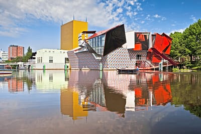 Bunte moderne Gebäude spiegeln sich in einem ruhigen Fluss.