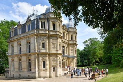 Gruppe von Menschen vor historischem Gebäude im Park.