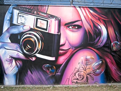 Graffiti einer Frau mit Kamera und Rose.
