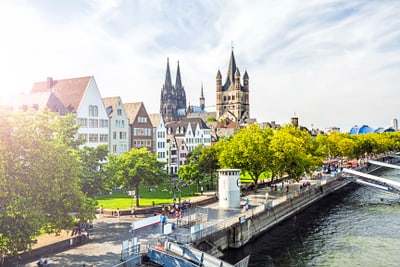 Blick auf Kölner Rheinpromenade mit Dom und Bäumen.