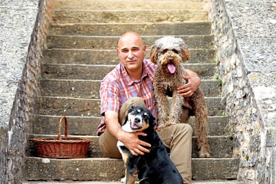Mann mit zwei Hunden auf einer Steintreppe.