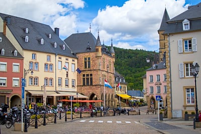 Historischer Platz mit bunten Gebäuden und Cafés unter blauem Himmel.