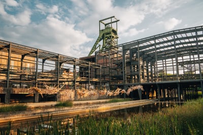 Industrielle Architektur mit grünem Turm und Teich im Vordergrund.