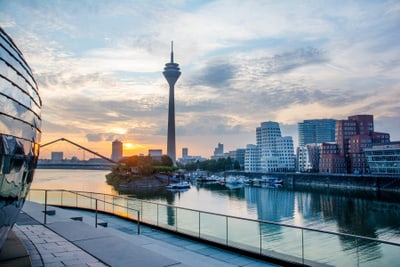 Stadtansicht mit Fernsehturm und Fluss bei Sonnenuntergang.