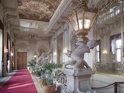 Barocke Galerie mit Statuen, Spiegeln und bemalter Decke.