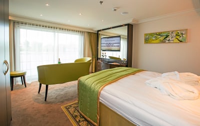 Hotelzimmer mit grünem Sofa und grossem Bett.