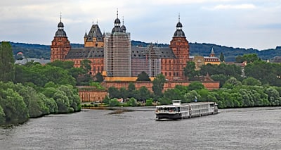 Schiff auf Fluss vor historischem Schloss mit Gerüst.