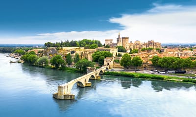 Stadtansicht von Avignon mit Fluss und Brücke bei klarem Himmel.
