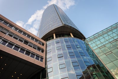 Moderne Glas- und Stahlararchitektur eines hohen Gebäudes vor blauem Himmel.