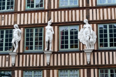Fassade mit Fachwerk und weissen Statuen.