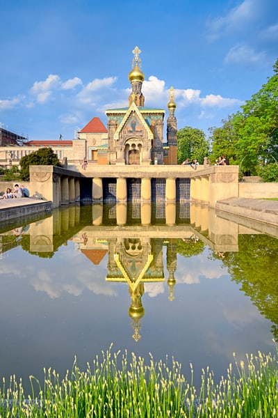 Russische Kapelle mit Spiegelbild im Wasser, blauer Himmel.