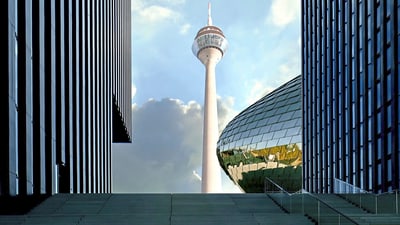 Turm zwischen modernen Gebäuden mit glänzender Fassade.