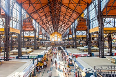 Grosse, belebte Markthalle mit hohen Decken und Ständen.