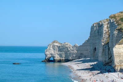 Kreidefelsen am Meer mit Strand und Menschen bei sonnigem Wetter.