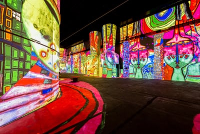 Bunte digitale Kunstprojektionen auf Wänden in einem dunklen Raum.