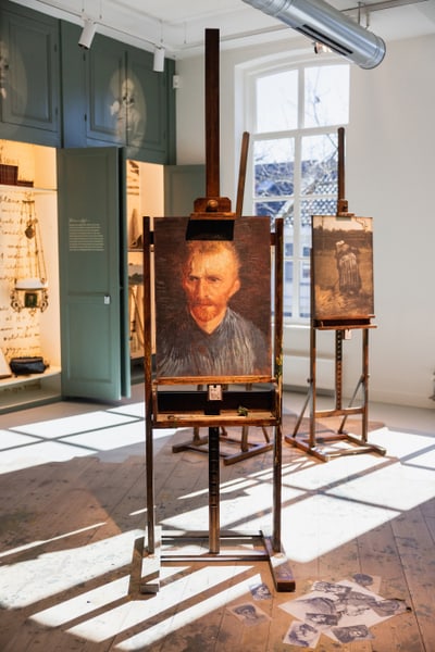 Ein Kunststudio mit Staffeleien und Gemälden in einem hellen Raum.