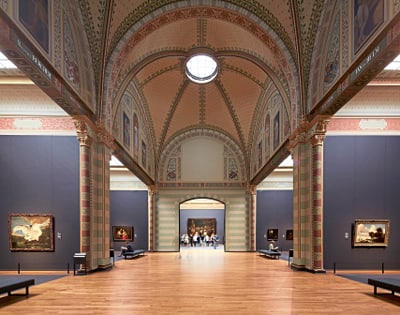 Innenansicht einer kunstvollen Museumshalle mit Gemälden.