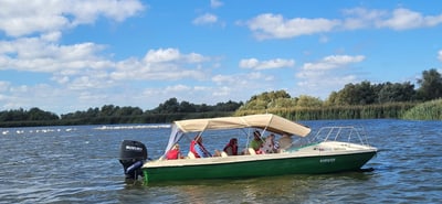 Motorboot mit Personen auf einem See unter blauem Himmel.